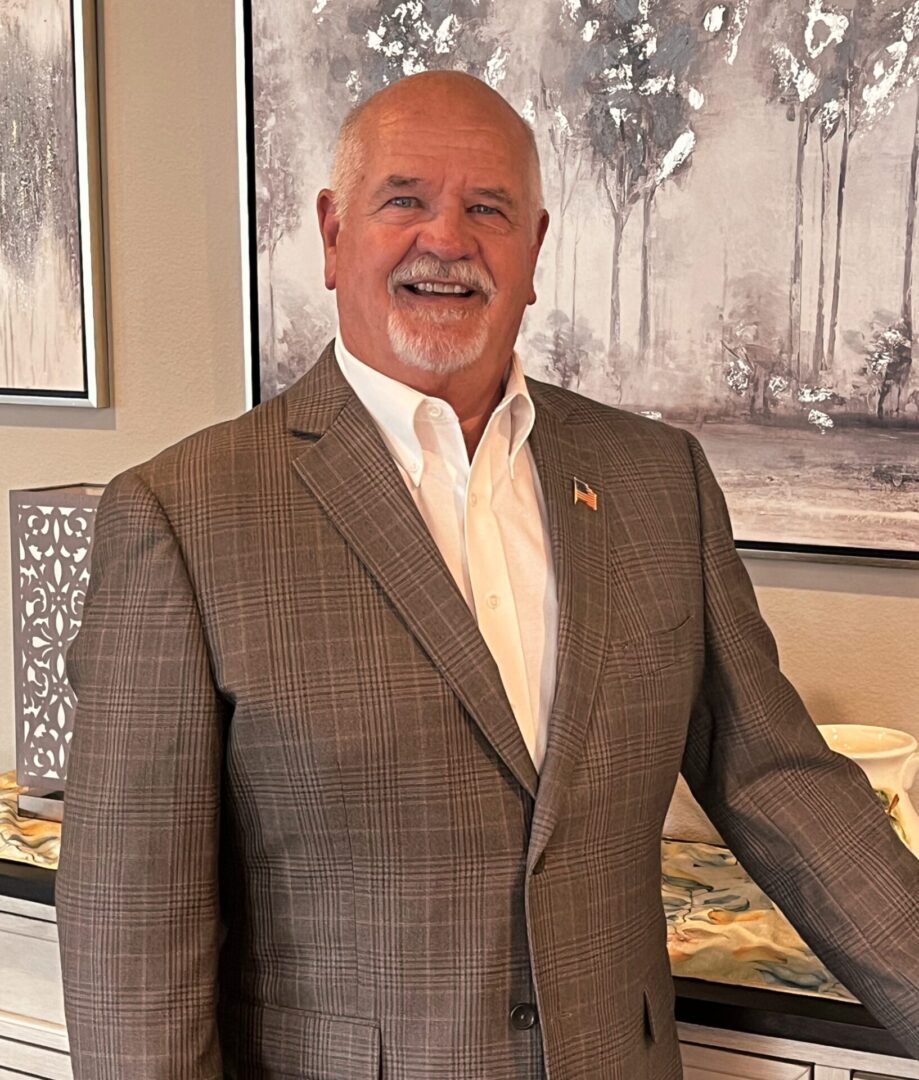 Smiling man in suit, standing indoors.